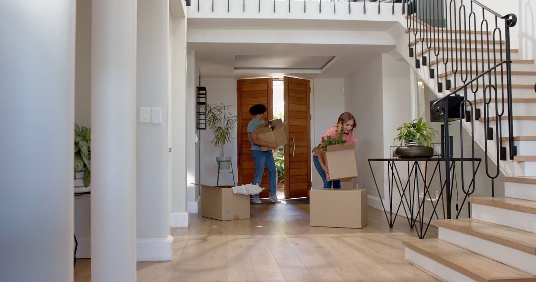 Couple Unpacking Boxes in New Home Foyer with Wooden Flooring and Modern Decor