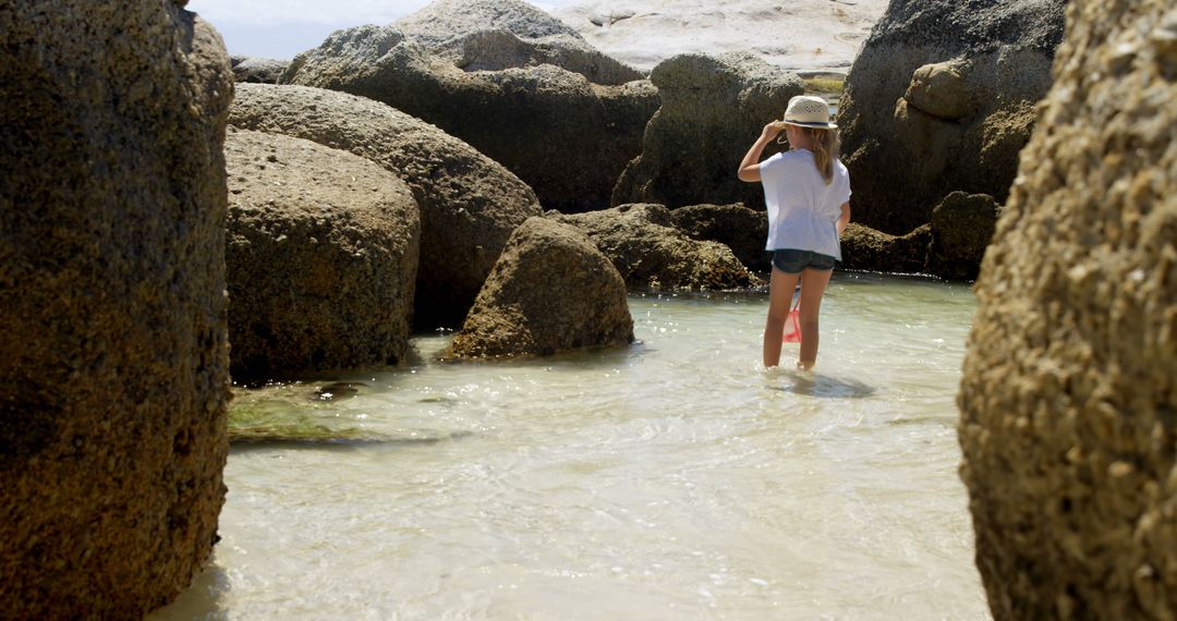 Woman Exploring Rocky Beach with Clear Water on Sunny Day - Free Images, Stock Photos and Pictures on Pikwizard.com