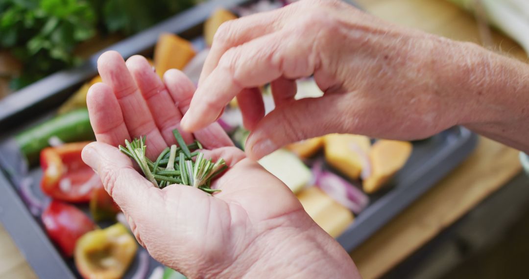 Elderly Hands Sprinkling Fresh Herbs Over Colorful Vegetables - Free Images, Stock Photos and Pictures on Pikwizard.com