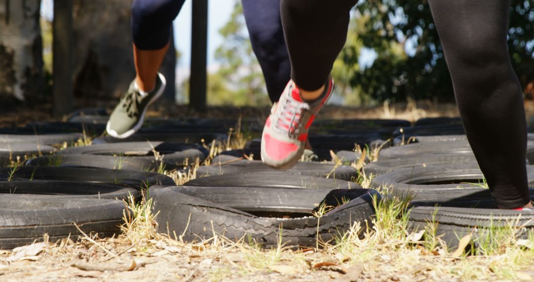 Participants Running Through Tire Obstacles During Outdoor Fitness Training - Free Images, Stock Photos and Pictures on Pikwizard.com