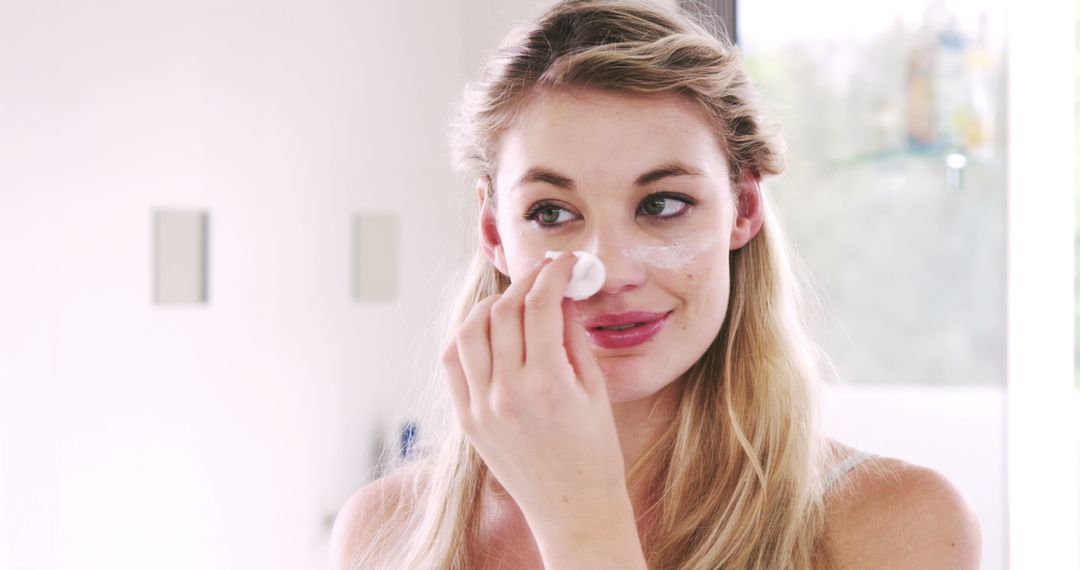 Young Woman Applying Face Cream in Bathroom - Free Images, Stock Photos and Pictures on Pikwizard.com