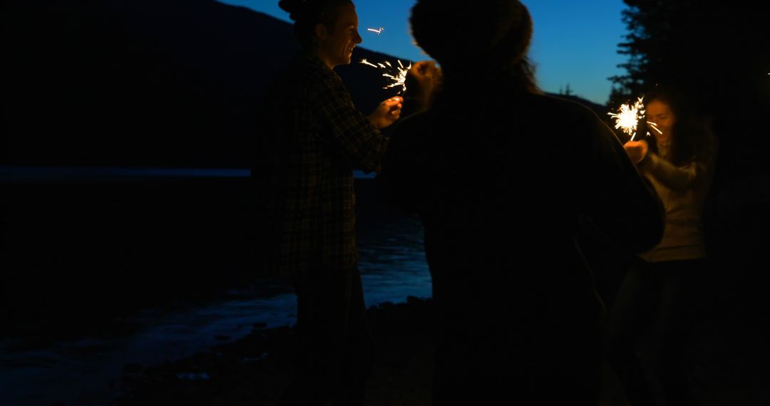 Friends Celebrating with Sparklers at Night by Lakeside - Free Images, Stock Photos and Pictures on Pikwizard.com