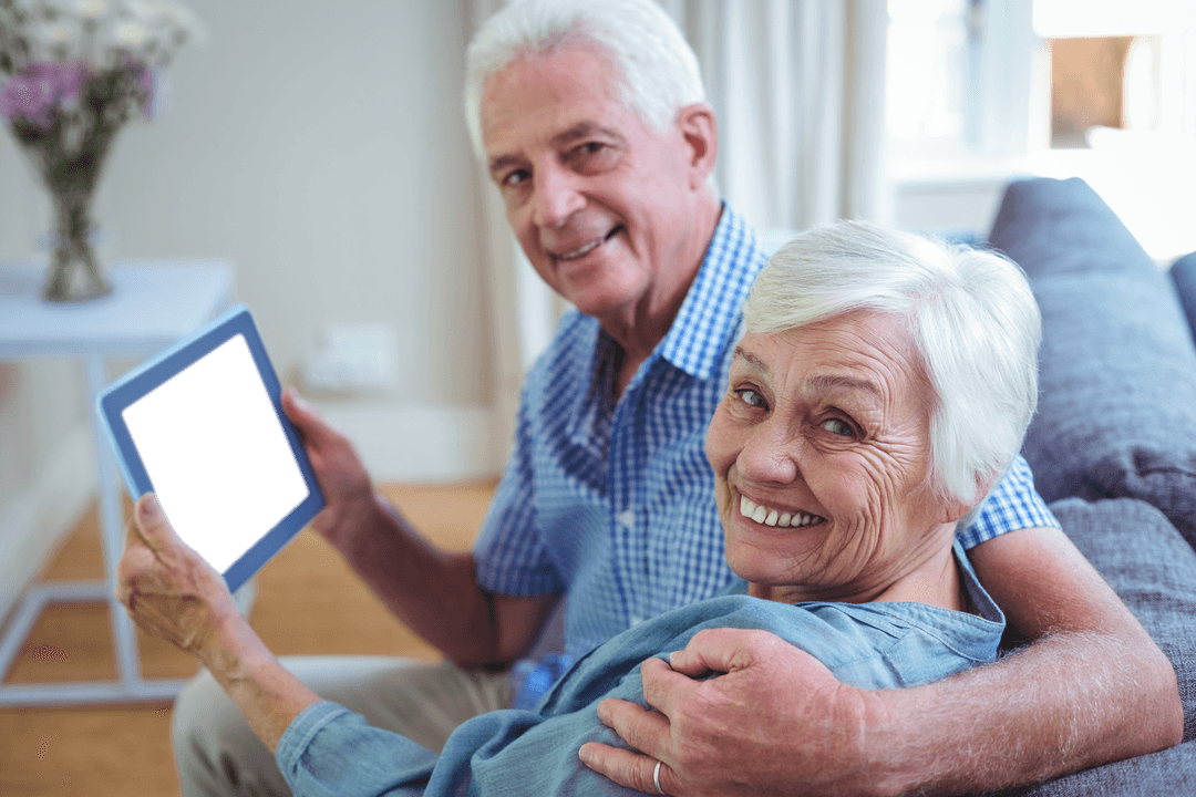 Senior Couple on Sofa Holding Transparent Tablet in Cozy Home