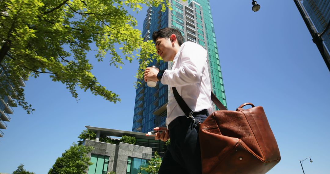 Man Walking in Urban Cityscape Holding Coffee and Phone - Free Images, Stock Photos and Pictures on Pikwizard.com