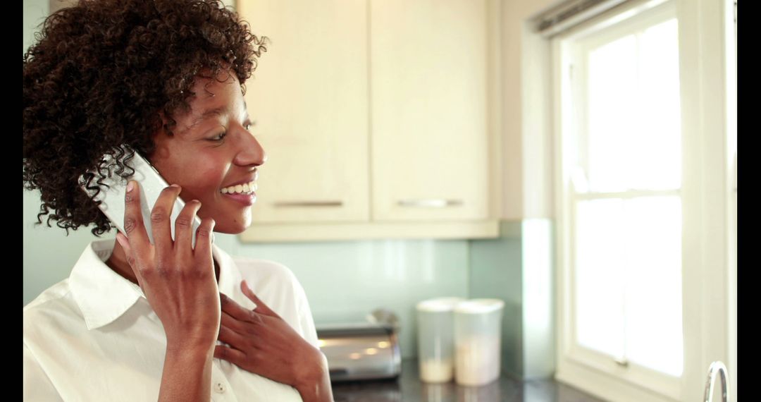 Smiling Woman Talking on Phone in Bright Kitchen - Free Images, Stock Photos and Pictures on Pikwizard.com