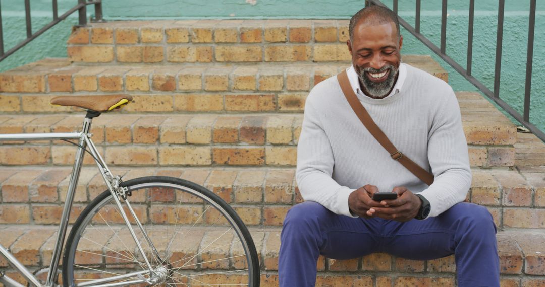 Smiling Man Sitting on Steps Using Smartphone with Bicycle - Free Images, Stock Photos and Pictures on Pikwizard.com