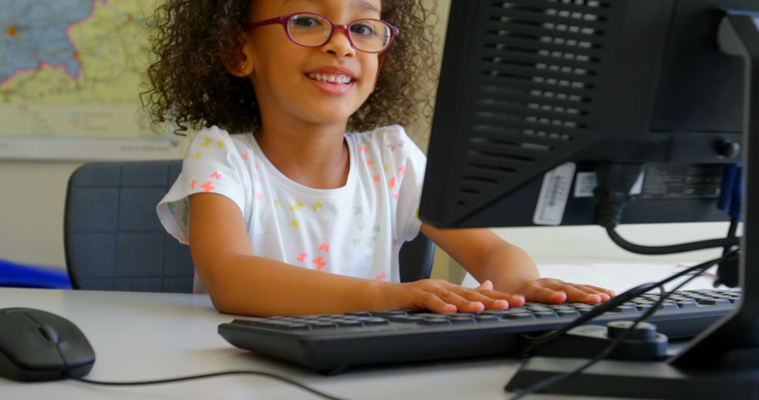 Happy Schoolgirl Using Desktop Computer in Classroom