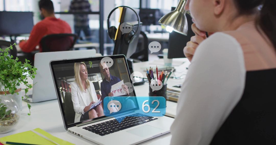 Leaning professional woman watching laptop with chat overlays and 62 notifications at desk
