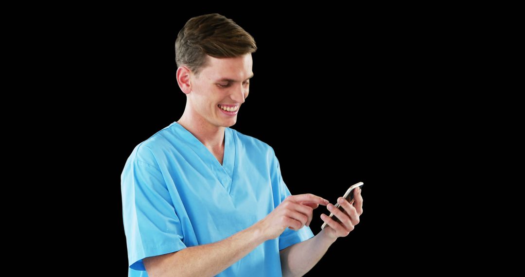 Male Nurse in Scrubs Smiling While Using Smartphone on Black Background - Free Images, Stock Photos and Pictures on Pikwizard.com