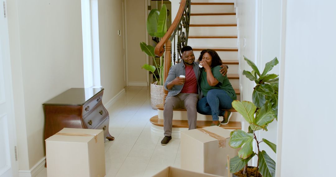 Joyful Couple Relaxing on Staircase with Coffee in New Home