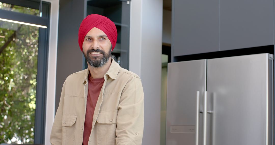 Smiling Man in Red Turban Relaxing in Modern Home Kitchen