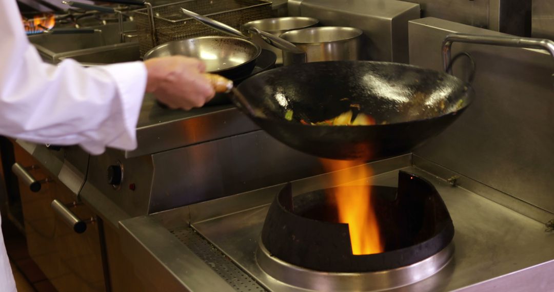 Chef Tossing Vegetables Over Flame in Professional Kitchen