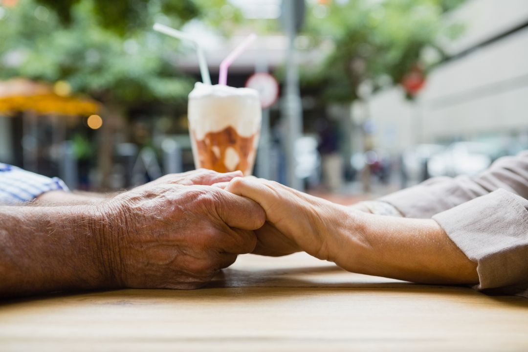 Elderly Couple Holding Hands in Outdoor Cafe - Free Images, Stock Photos and Pictures on Pikwizard.com