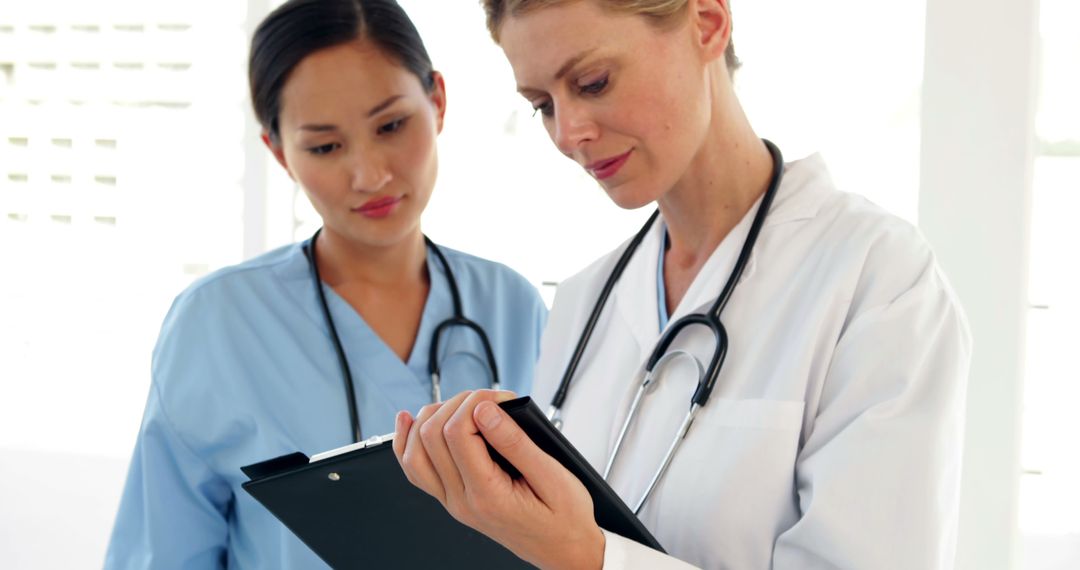 Female Doctors Discussing Patient Medical Chart in Bright Clinic - Free Images, Stock Photos and Pictures on Pikwizard.com