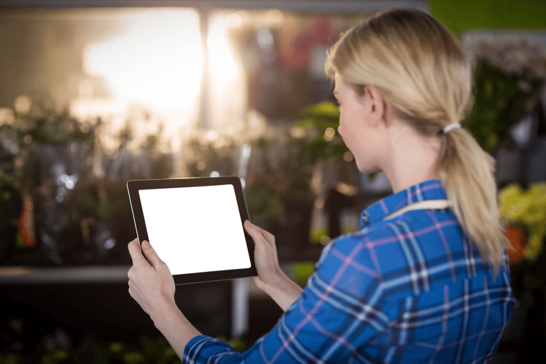 Florist Using Transparent Tablet in Shop Greenhouse Setting