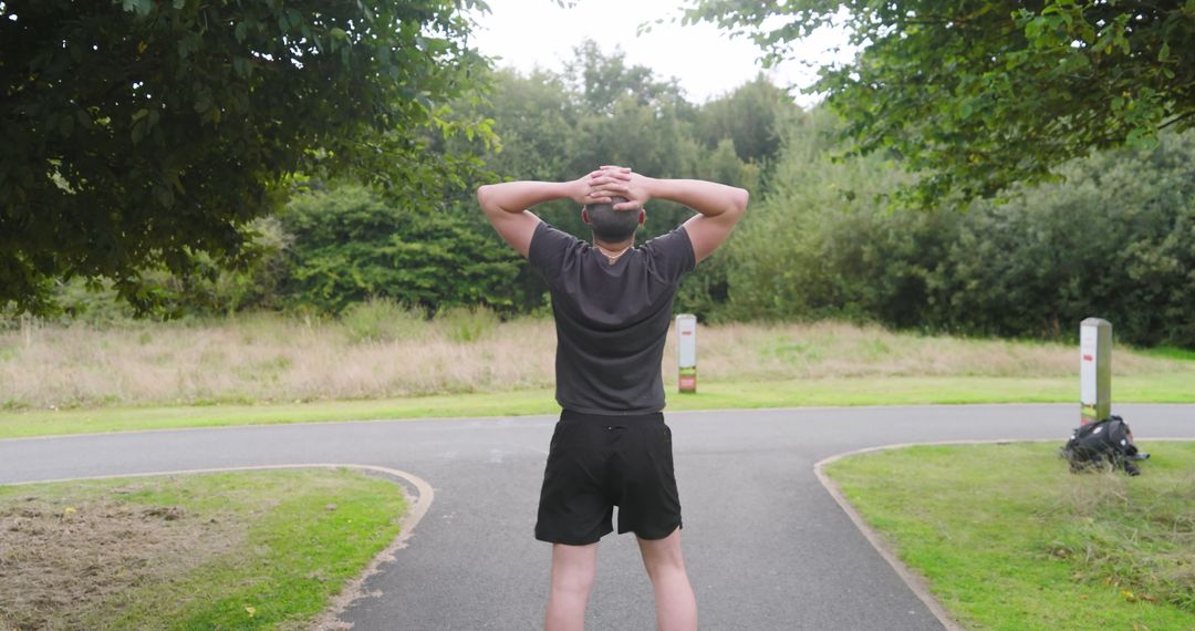 Man Jogging in Park with Lush Foliage on Sunny Day