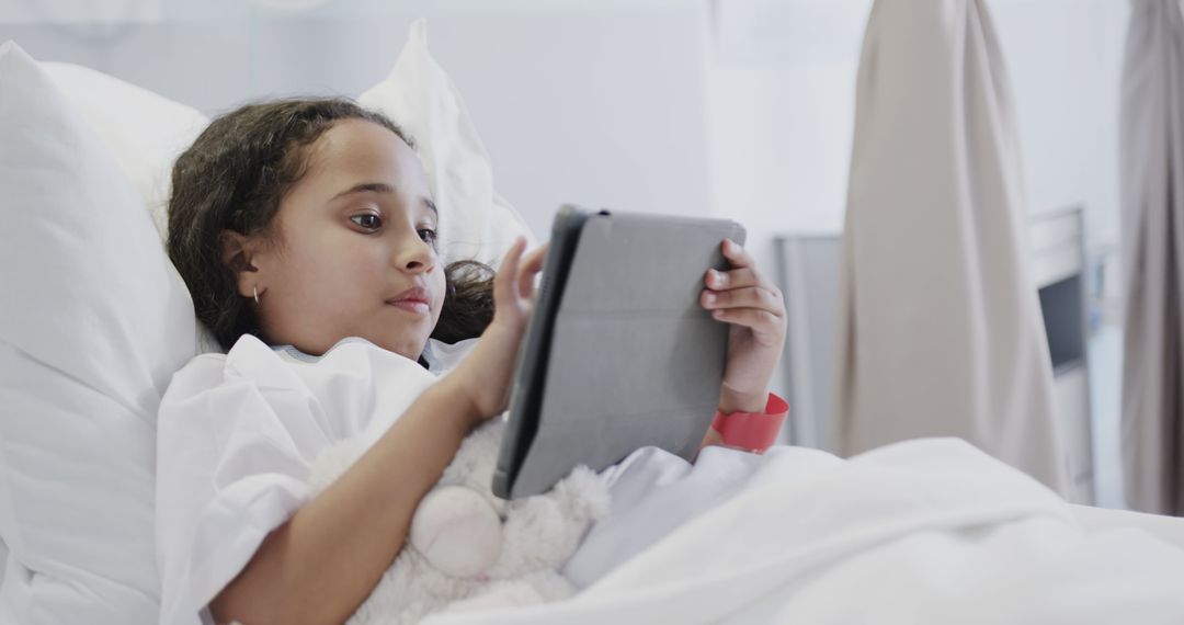 Young Girl Using Tablet in Hospital Bed with Teddy Bear - Free Images, Stock Photos and Pictures on Pikwizard.com