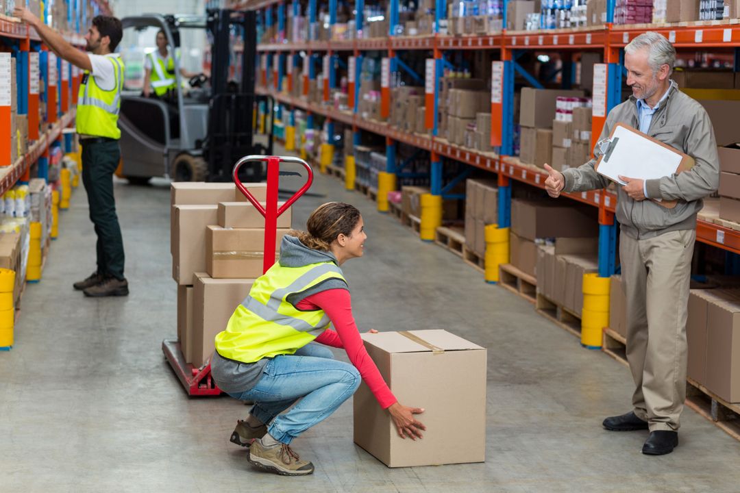 Warehouse manager showing thumbs up to female worker while carrying cardboard boxes - Free Images, Stock Photos and Pictures on Pikwizard.com
