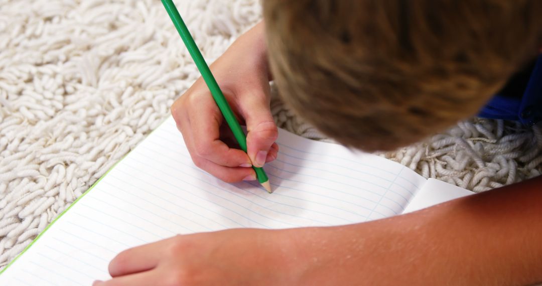 Child Lying on Carpet Drawing with Green Pencil