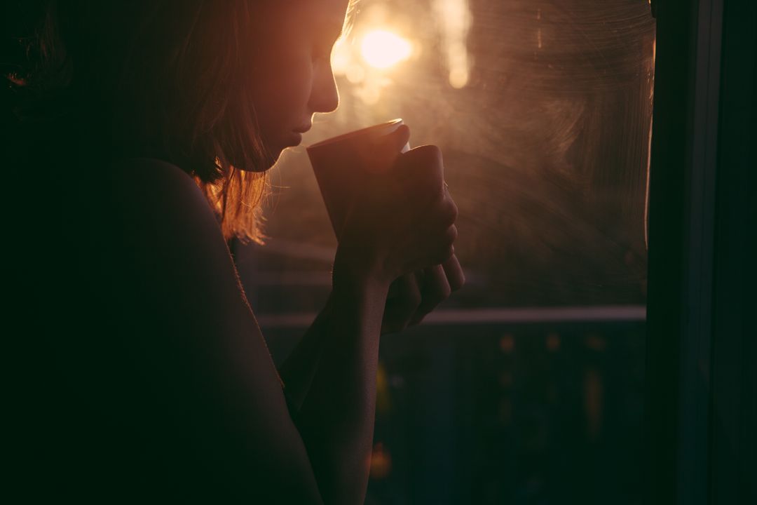 Woman Drinking Coffee by Window at Sunrise with Soft Sunlight - Free Images, Stock Photos and Pictures on Pikwizard.com