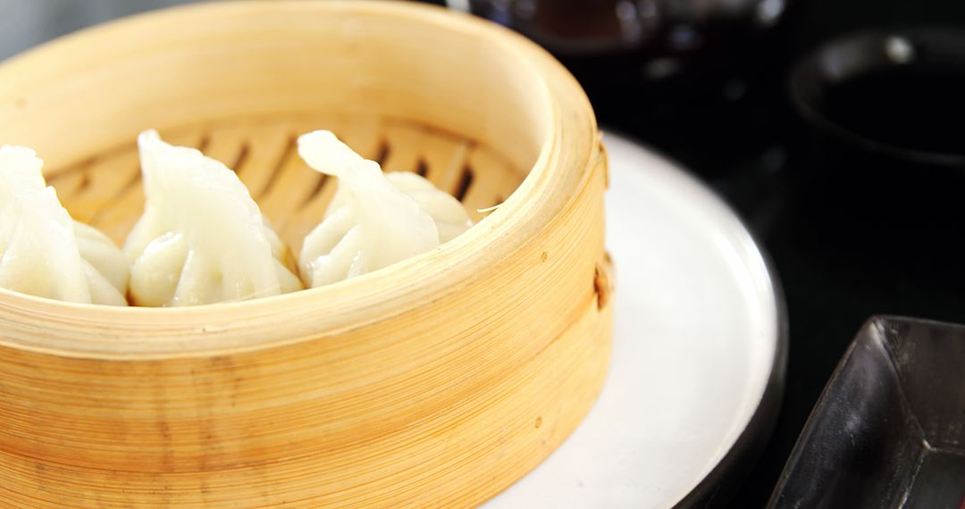 Steaming dumplings in bamboo basket on dining table - Free Images, Stock Photos and Pictures on Pikwizard.com