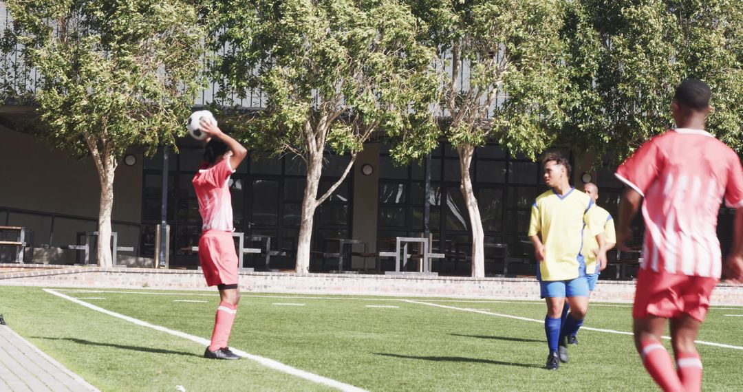 Players Engaged in Dynamic Soccer Match on Green Field