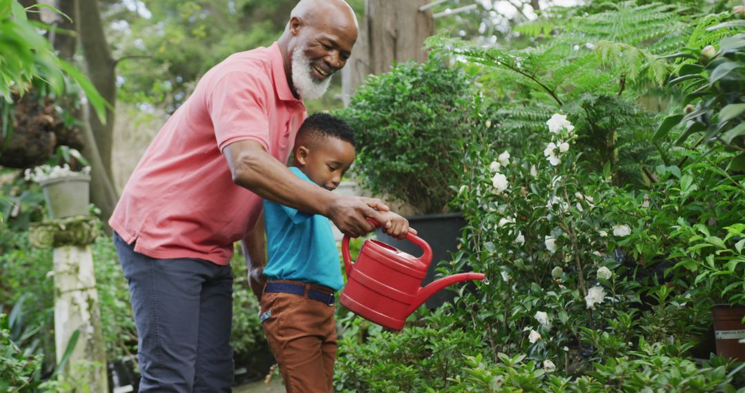 Happy senior african american man with his grandson watering plants in garden - Free Images, Stock Photos and Pictures on Pikwizard.com