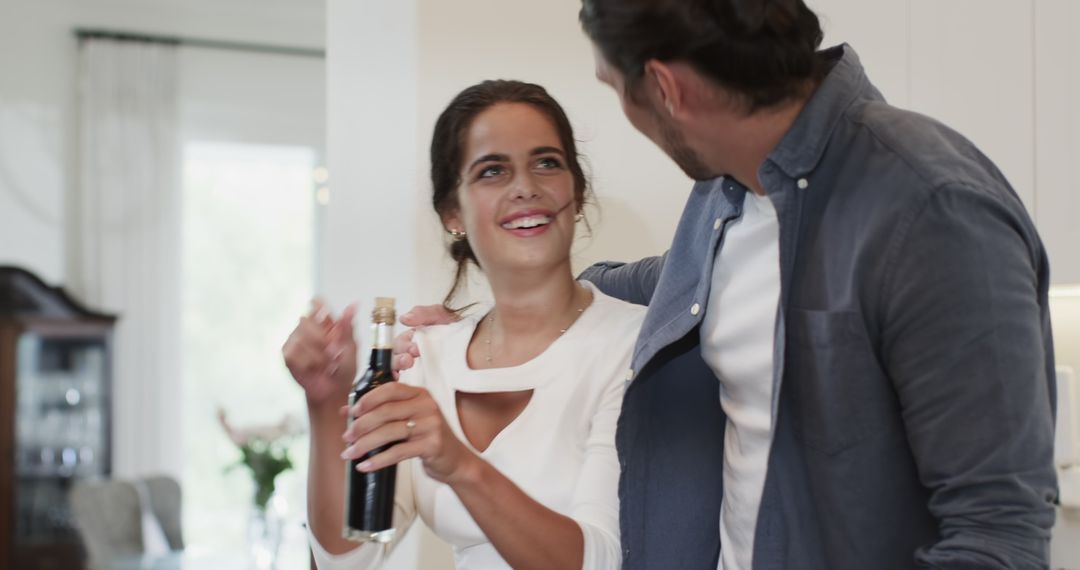 Couple Laughing While Celebrating with Bottle at Home