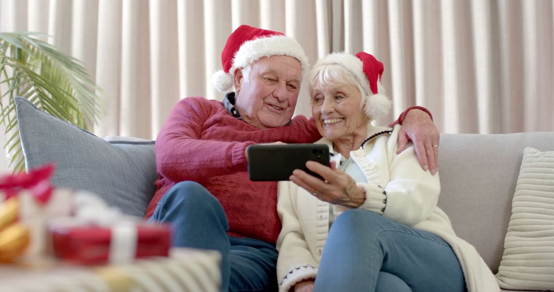 Happy Senior Couple in Santa Hats Taking a Selfie During Christmas - Free Images, Stock Photos and Pictures on Pikwizard.com