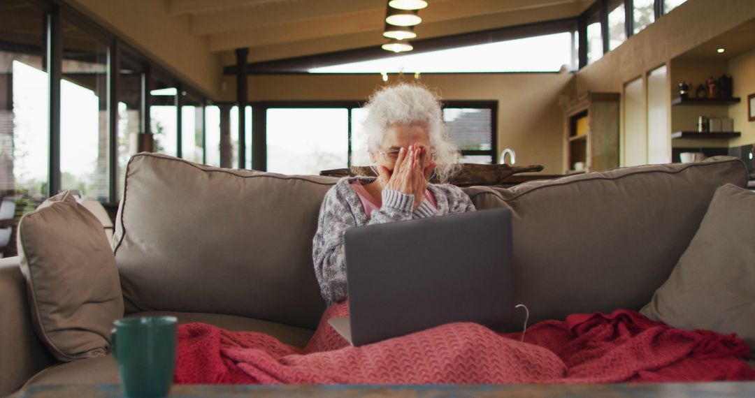 Senior Woman Sitting on Couch Using Laptop in Cozy Home - Free Images, Stock Photos and Pictures on Pikwizard.com