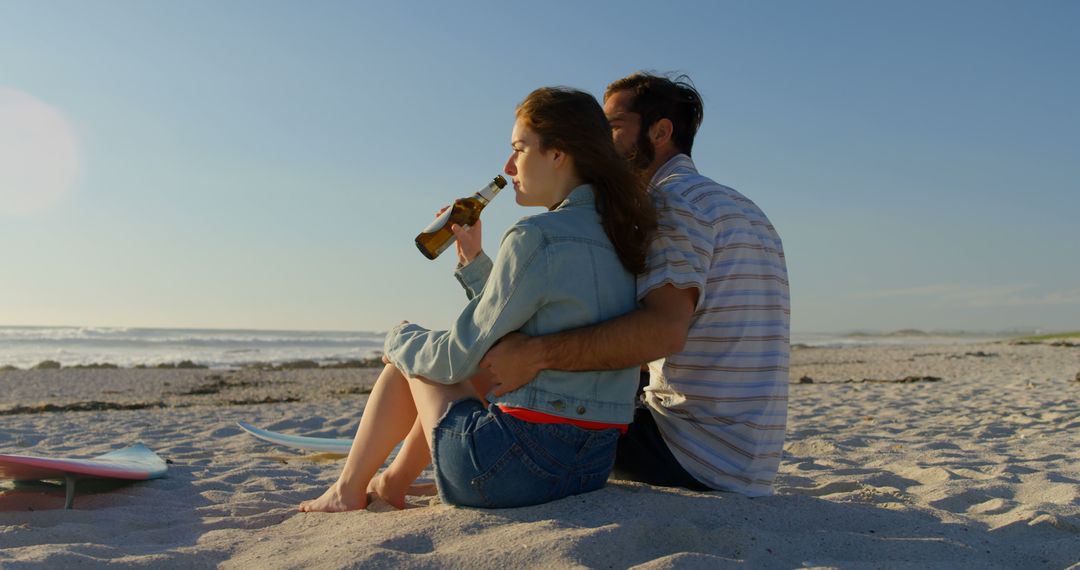 Couple Relaxing at Beach with Drinks During Sunset - Free Images, Stock Photos and Pictures on Pikwizard.com