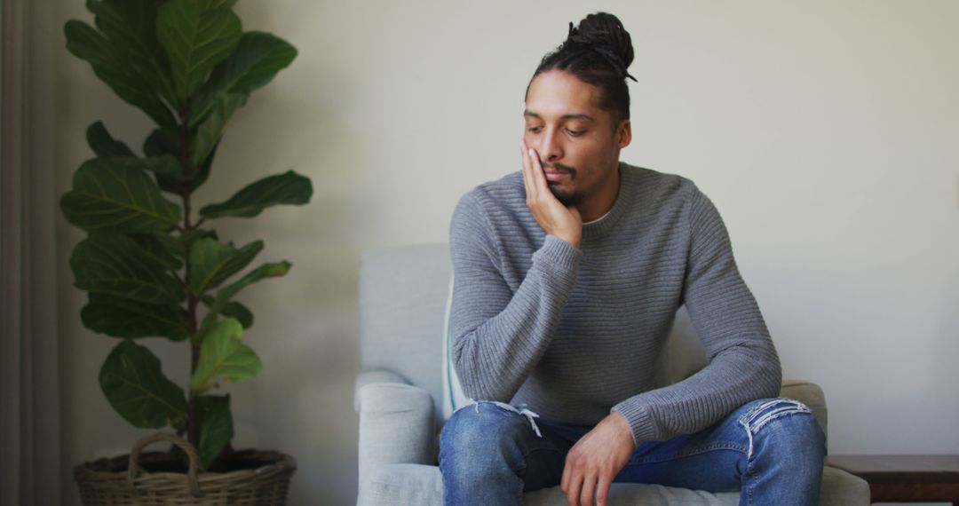 Reflective Biracial Man with Dreadlocks Sitting in Living Room - Free Images, Stock Photos and Pictures on Pikwizard.com