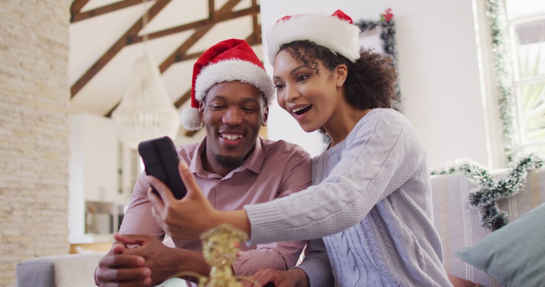 Happy african american couple with santa hats having image call - Free Images, Stock Photos and Pictures on Pikwizard.com