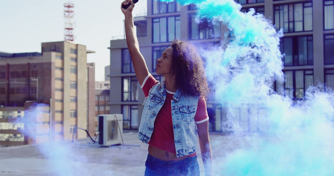 Young Woman Holding Blue Smoke Flare on Urban Rooftop - Free Images, Stock Photos and Pictures on Pikwizard.com