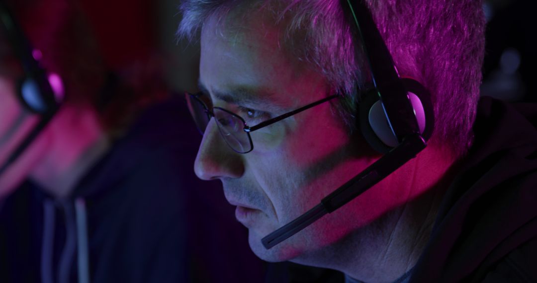 Middle-aged Man with Headset in Dark Office Lit by Neon Lights - Free Images, Stock Photos and Pictures on Pikwizard.com