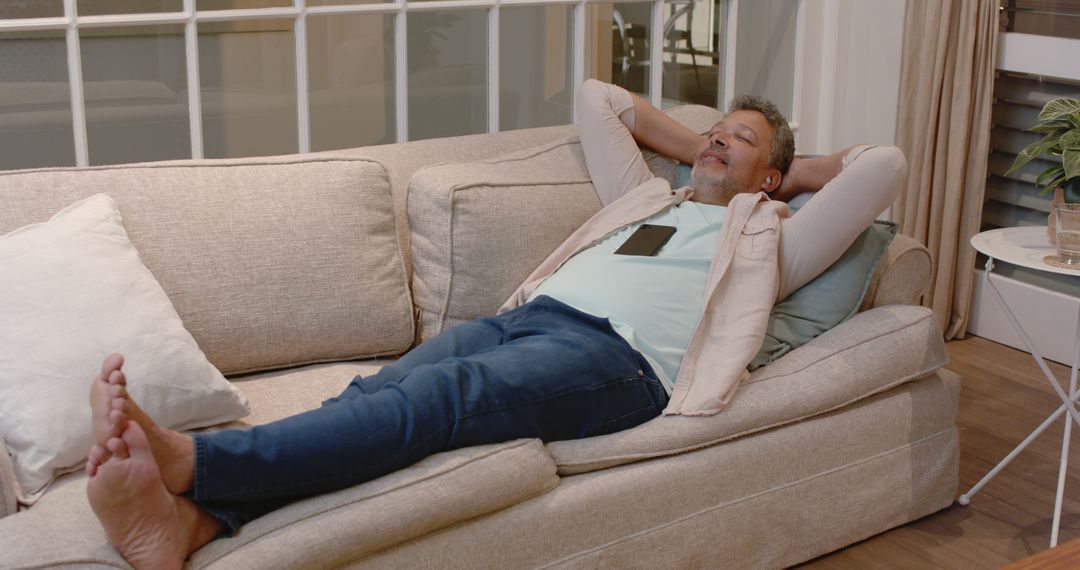 Senior Man Relaxing on Sofa with Smartphone