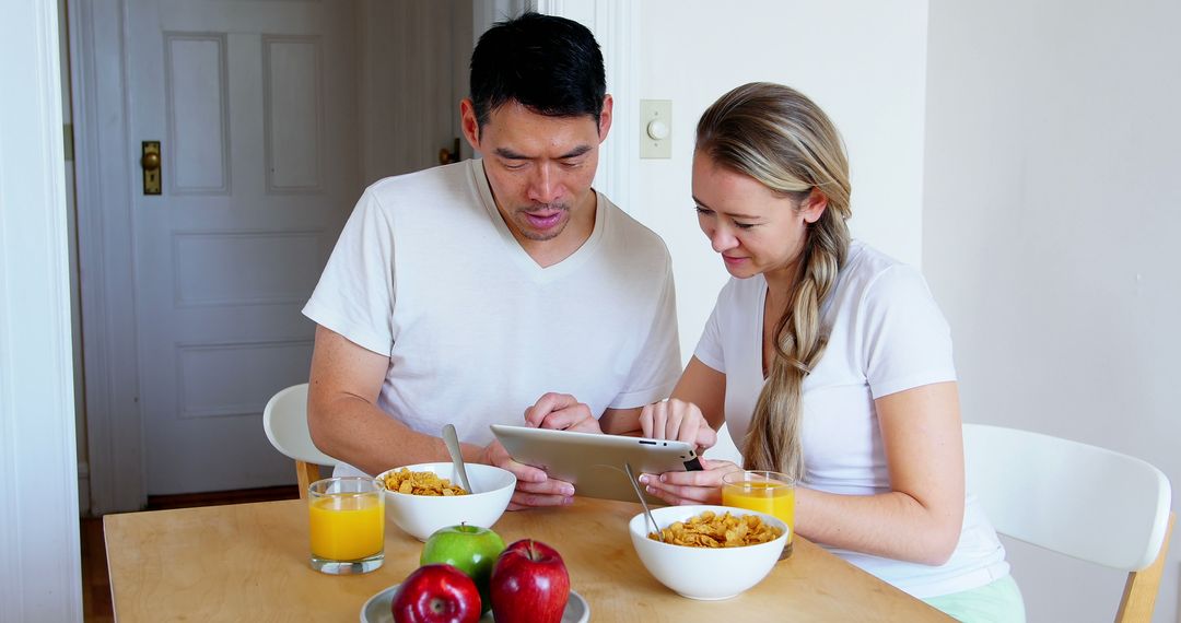 Couple Having Breakfast Using Tablet at Home