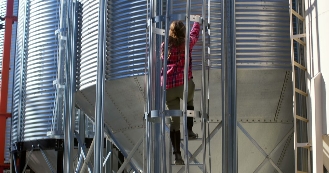 Rear view of caucasian female worker climbing ladder by storage tank - Free Images, Stock Photos and Pictures on Pikwizard.com