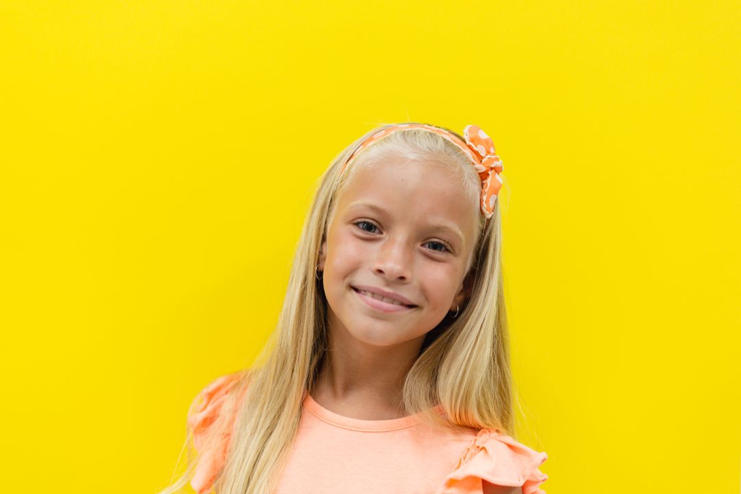 Portrait of smiling caucasian elementary schoolgirl with blond hair against yellow background - Free Images, Stock Photos and Pictures on Pikwizard.com