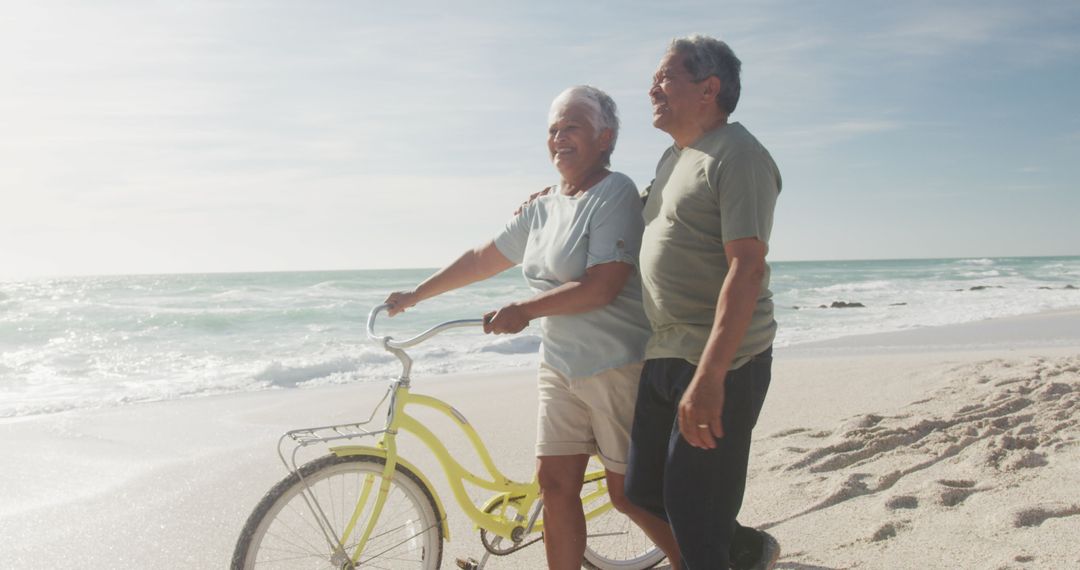 Senior Couple Enjoying Beach Walk with Bicycle at Sunset