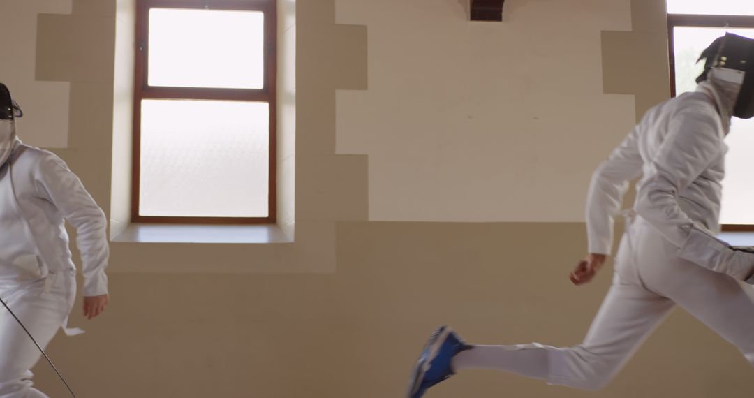 An athlete in uniform practicing fencing indoors near a window - Free Images, Stock Photos and Pictures on Pikwizard.com