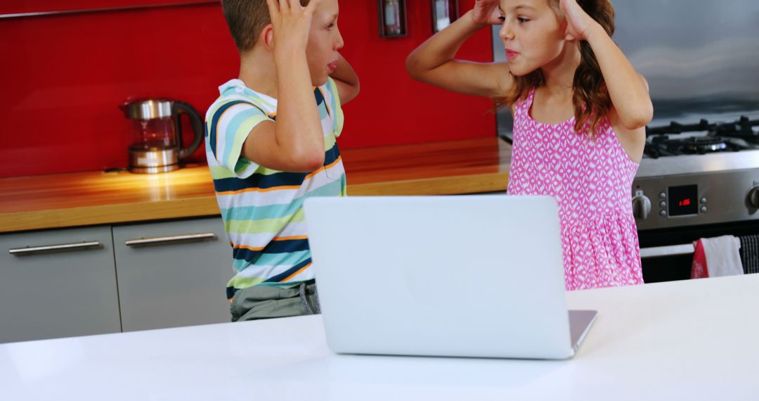 Two children exhibit frustration over a computer issue in the kitchen. - Free Images, Stock Photos and Pictures on Pikwizard.com