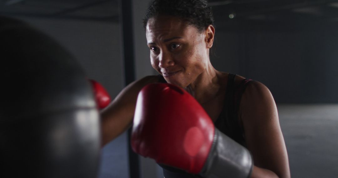 Focused Female Boxer Training with Punching Bag in Gym - Free Images, Stock Photos and Pictures on Pikwizard.com