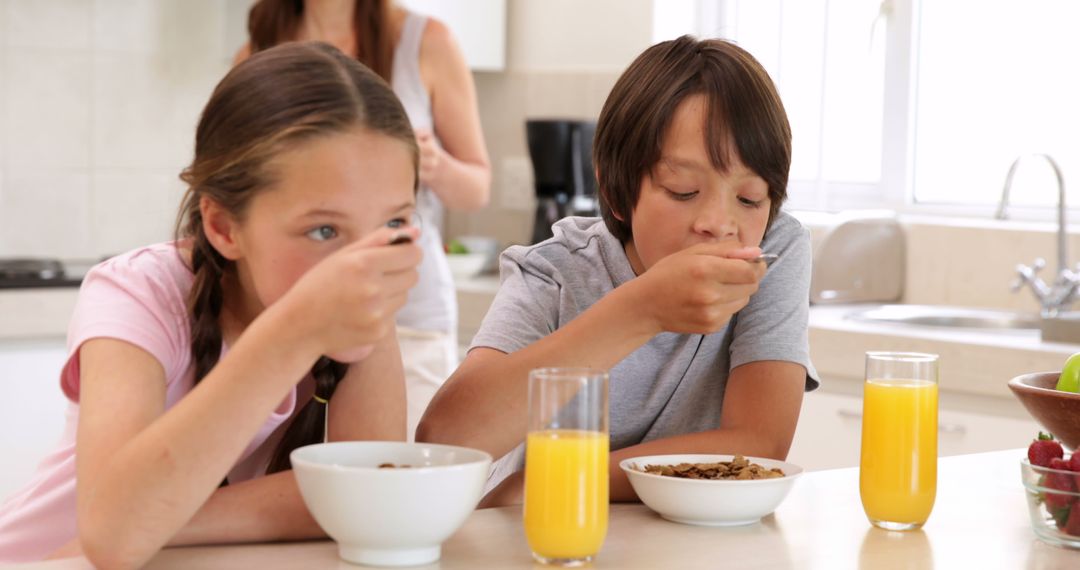 Children Eating Breakfast with Cereal and Juice in Kitchen - Free Images, Stock Photos and Pictures on Pikwizard.com