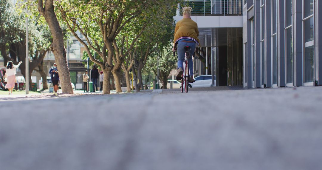 Person Cycling on Urban Street with People and Trees in Background - Free Images, Stock Photos and Pictures on Pikwizard.com