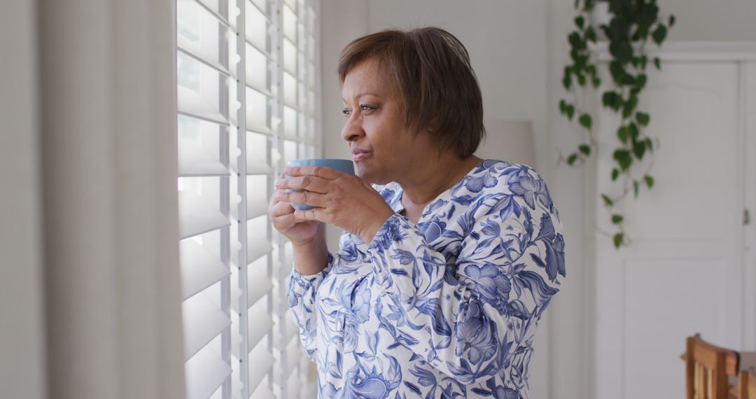 Mature Woman Drinking Coffee While Looking Out Window - Free Images, Stock Photos and Pictures on Pikwizard.com