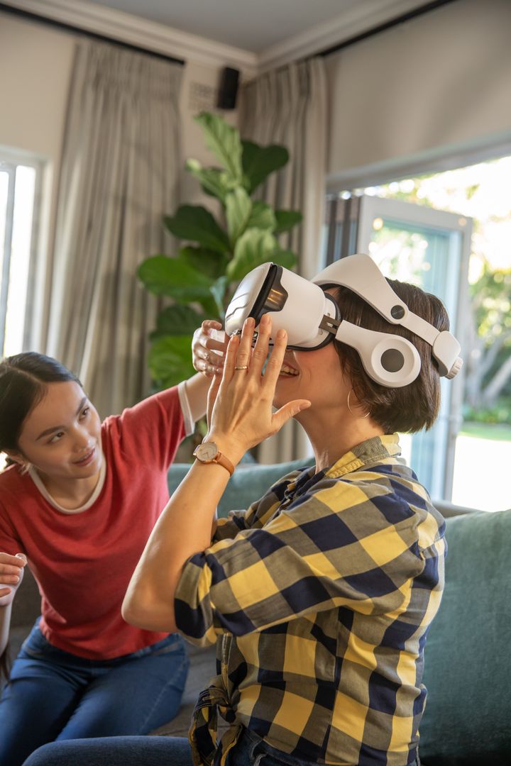 Daughter Assisting Mother Wearing VR Headset in Comfortable Home Setting