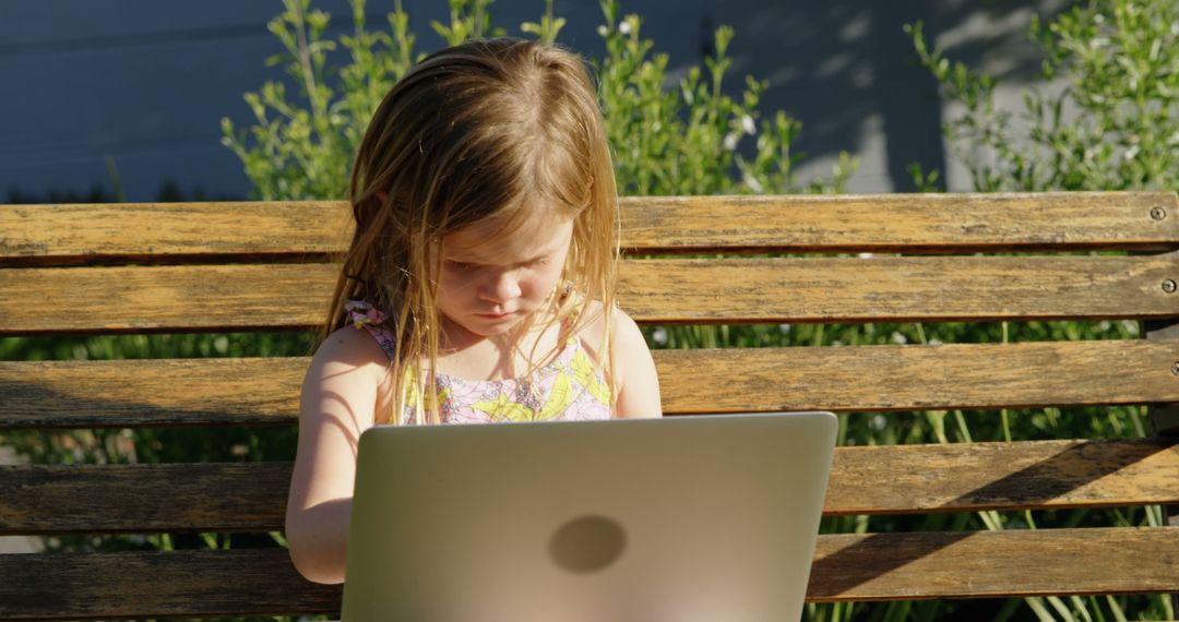 Young Girl Concentrating on Laptop While Sitting on Outdoor Bench - Free Images, Stock Photos and Pictures on Pikwizard.com