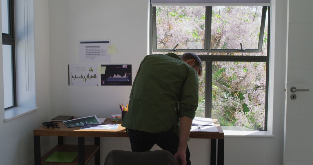 Man Analyzing Data at Home Office Desk Next to Window - Free Images, Stock Photos and Pictures on Pikwizard.com