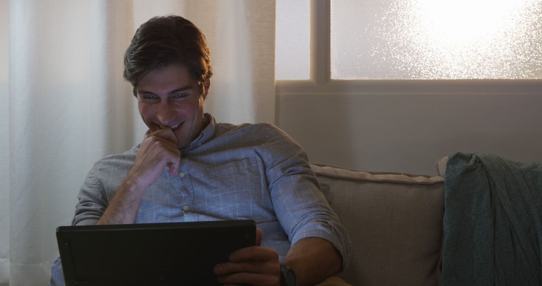 Man Smiling While Using Tablet at Home in Cozy Evening Lighting - Free Images, Stock Photos and Pictures on Pikwizard.com